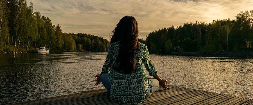 Lady doing yoga by the water. 